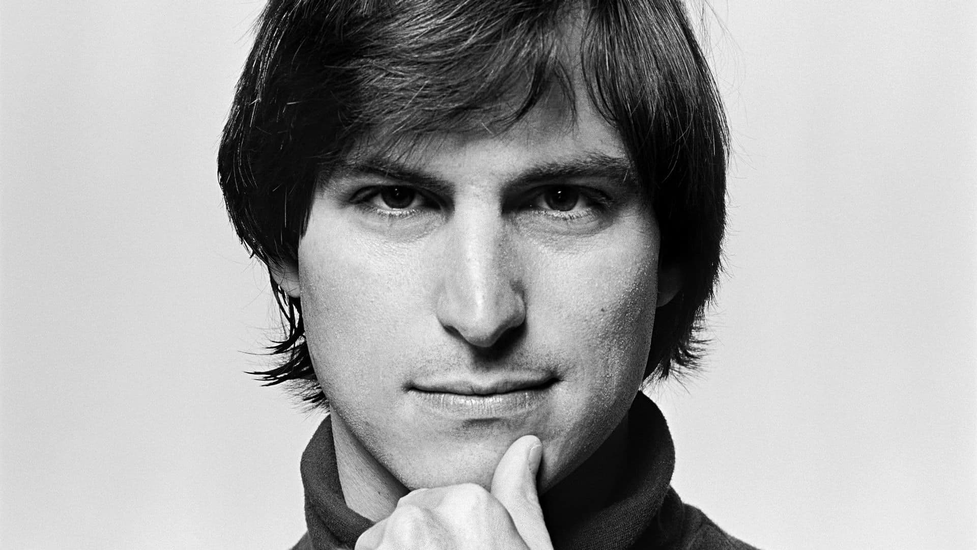 Black-and-white portrait of Steve Jobs, resting his chin on his hand.
